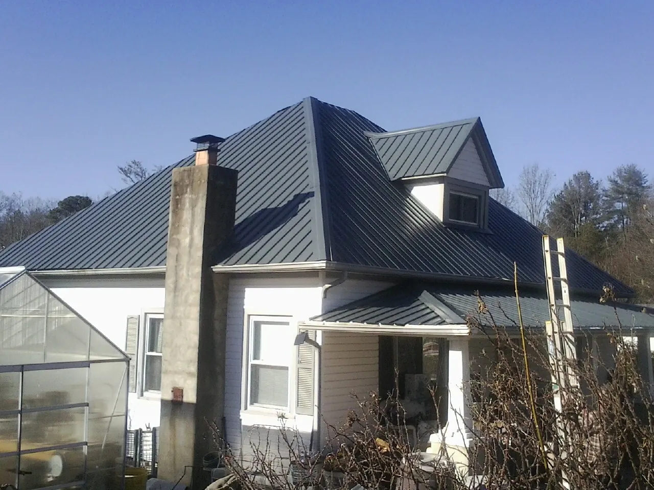 Dark blue standing seam metal roof on a white farmhouse with dormer — Slate & Tile Roof Repair by Roofing Brothers in Shasta Lake
