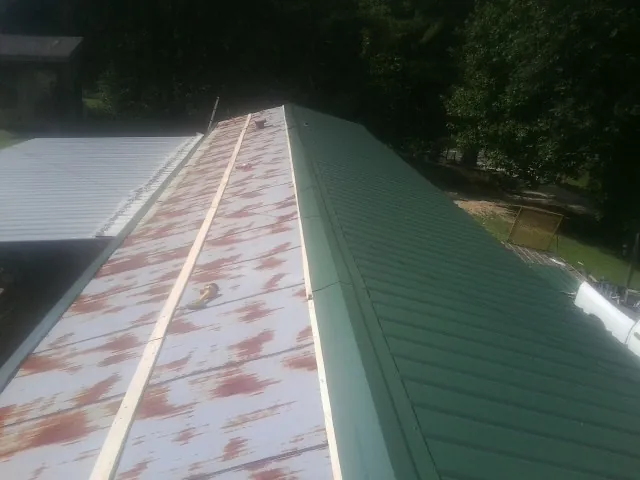 Old rusted panels beside newly installed green metal roofing — Wind Damage Roof Repair by Roofing Brothers in Shasta Lake
