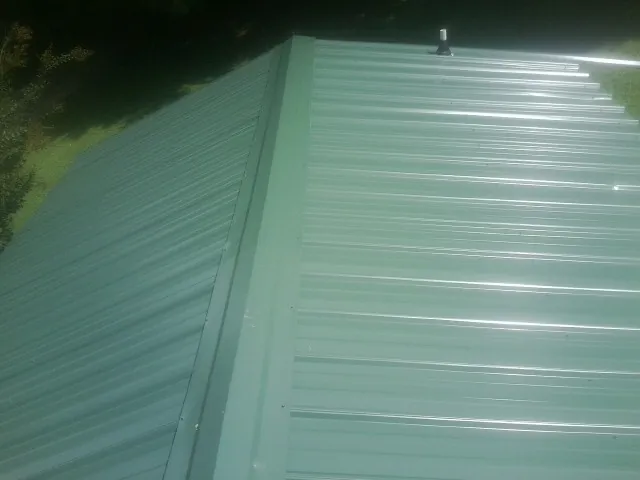 New green metal panels meeting at the ridge of a roof — Flat Roof Repair work by our crew in Shasta Lake