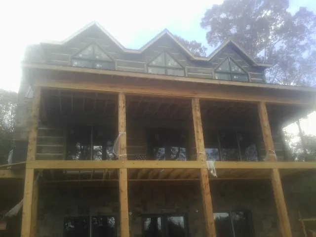 Dormers and porch framing on a large log home under construction — Roof Coating work by our crew in Shasta Lake