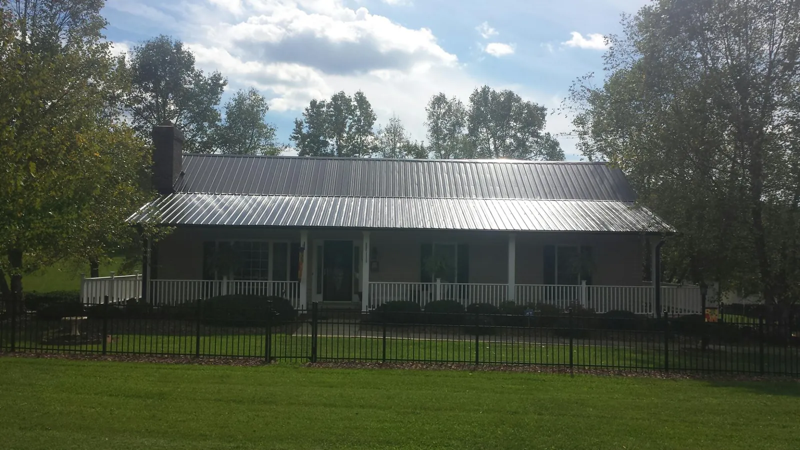 Gray metal roof on a brick ranch with a full width front porch — Gutter Guard Installation work by our crew in Shasta Lake