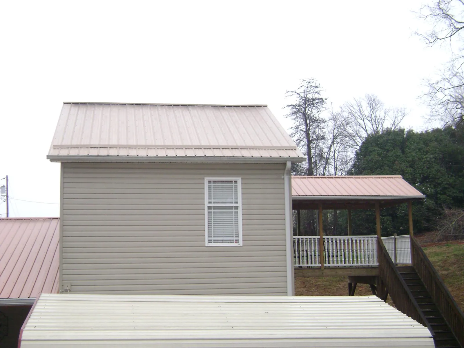 Tan metal roofs on a two story addition and attached porch, from a Roof Replacement job in Shasta Lake