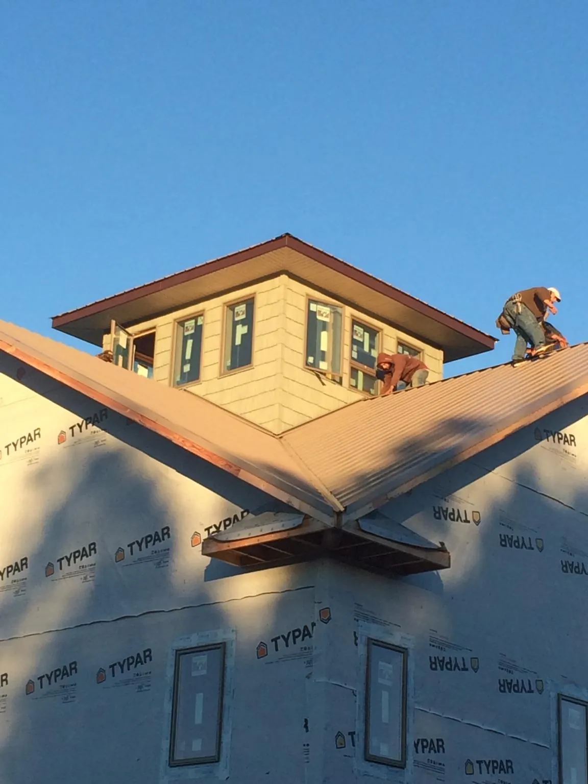 Roofers working around a rooftop cupola on a new metal roof at sunset — Roof Waterproofing in Shasta Lake by Roofing Brothers